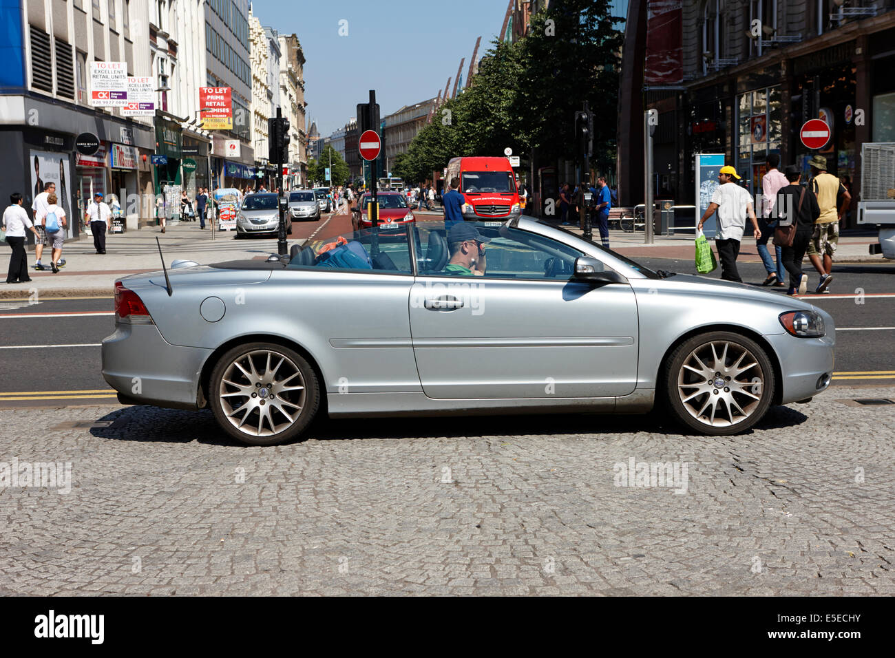 Uomo alla guida di una convertibile per Volvo auto su un luminoso giorno Belfast City Centre Foto Stock