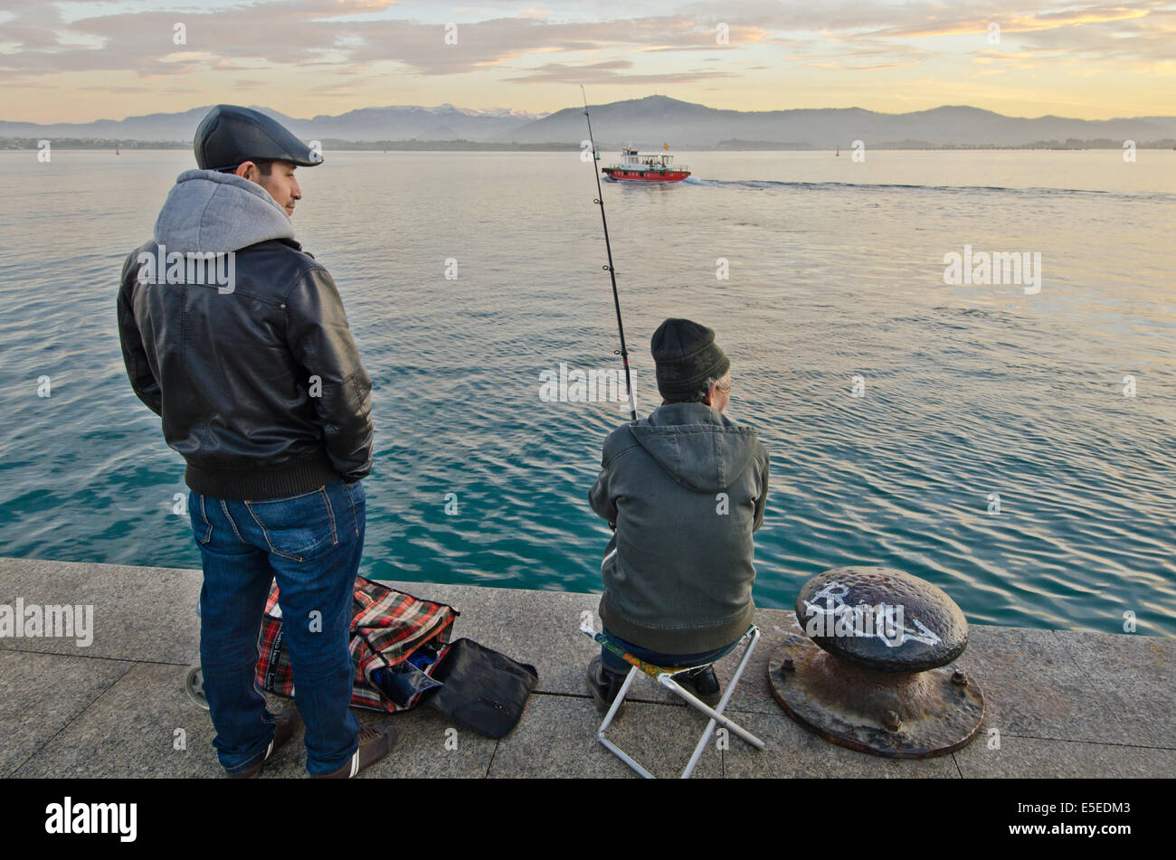 Un pescatore e un passante sul vecchio dock sul Paseo Pereda su Santander waterfront. In background, baia di Santander e li Foto Stock