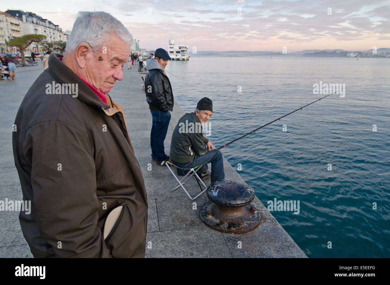 Un pescatore e i passanti sul vecchio dock sul Paseo Pereda su Santander waterfront. In background, baia di Santander può essere visto Foto Stock