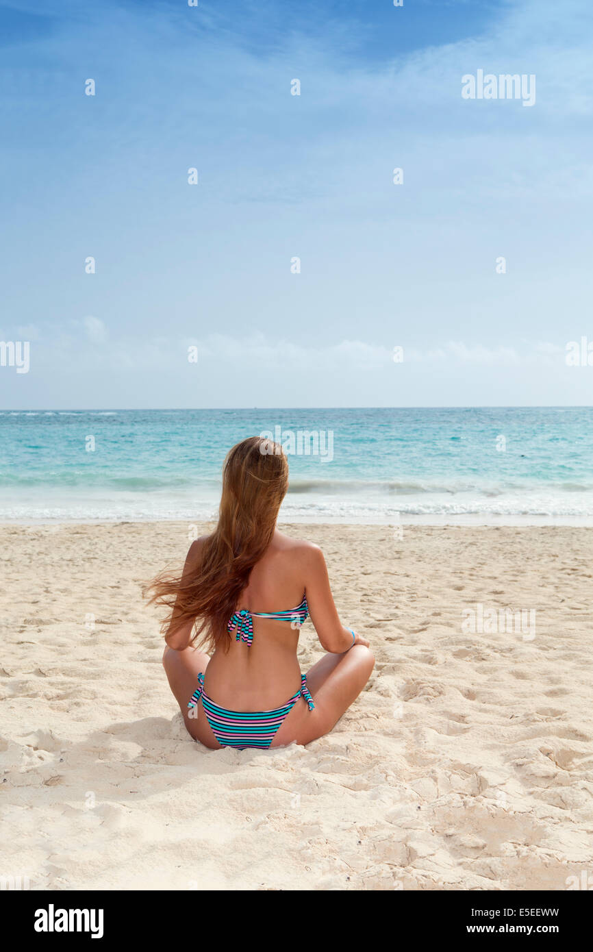 Una giovane donna seduta su una spiaggia dei Caraibi Foto Stock
