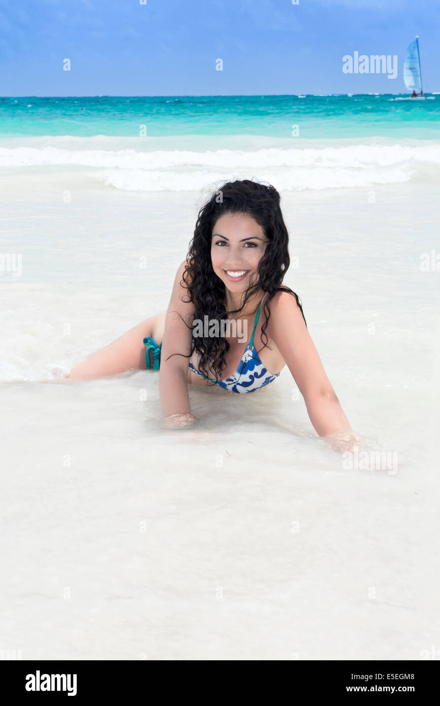 Una giovane e bella donna nel surf su un idilliaco spiaggia Caraibica Foto Stock