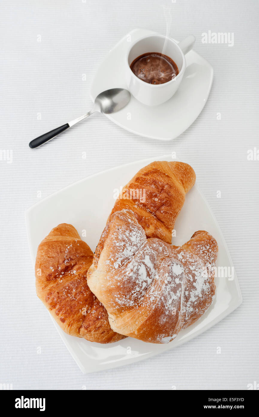 Prodotti da forno freschi croissants con tazza di caffè sulla tovaglia bianca Foto Stock