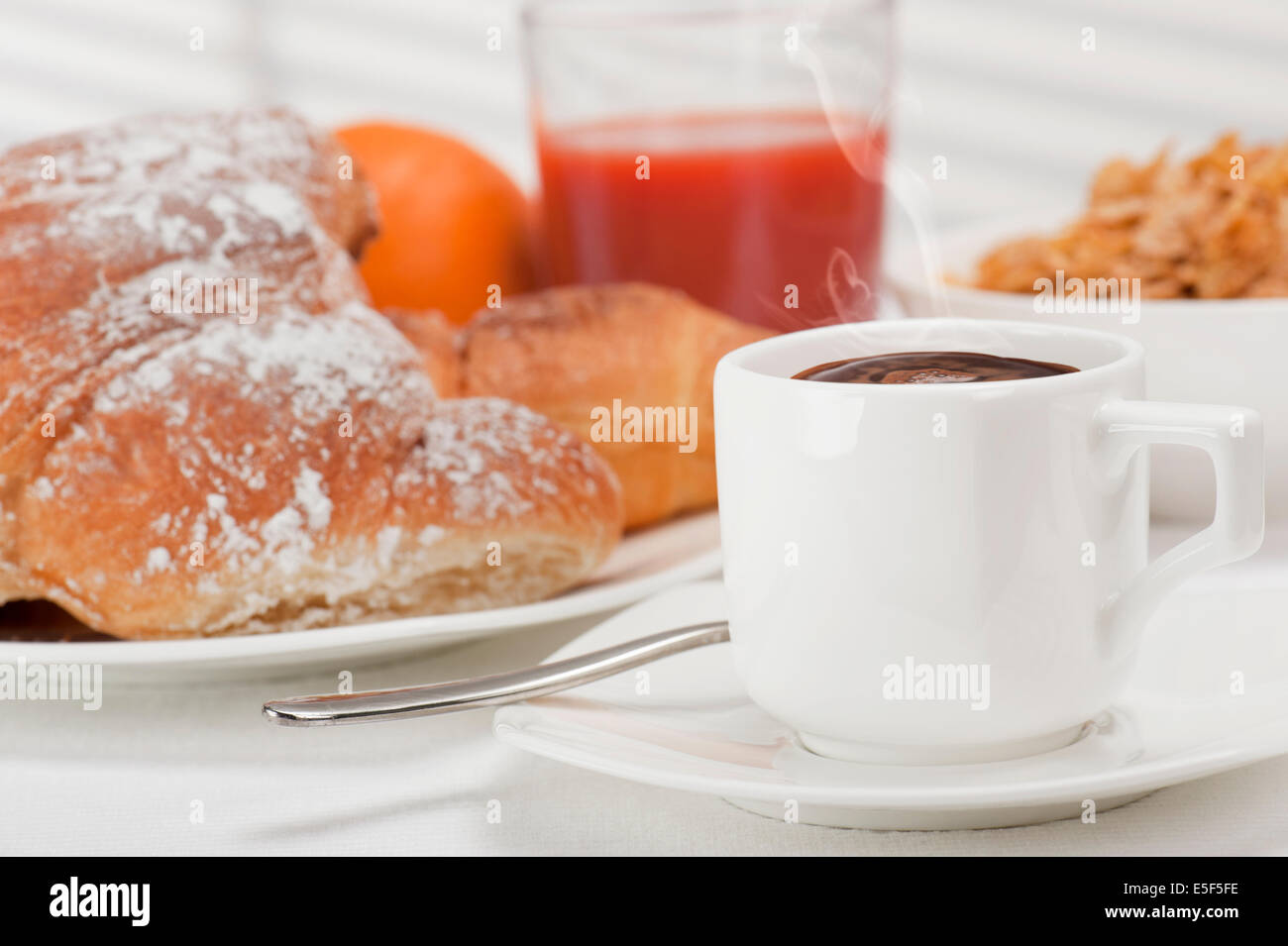 La prima colazione continentale con tazza di caffè, cornetti freschi, succo d'arancia e fiocchi di mais Foto Stock
