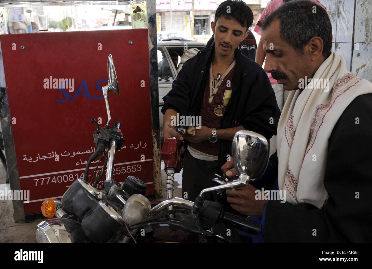 Sanaa, Yemen. Il 30 luglio, 2014. Yemenis riempire le loro moto con la benzina ad una stazione di benzina in Sanaa, Yemen, il 30 luglio 2014. Il governo yemenita ha aumentato il prezzo della benzina da 125 yemenita riyals (0,58 dollari USA) a 200 riyals per litro e disel da 100 riyals a 195 riyals Mercoledì, che ha scatenato proteste di massa nella capitale Sanaa. Manifestanti arrabbiati pneumatici bruciati e tagliato molte strade in Sanaa. Il governo ha distribuito più soldati per mantenere la sicurezza nella capitale. Credito: Mohammed Mohammed/Xinhua/Alamy Live News Foto Stock