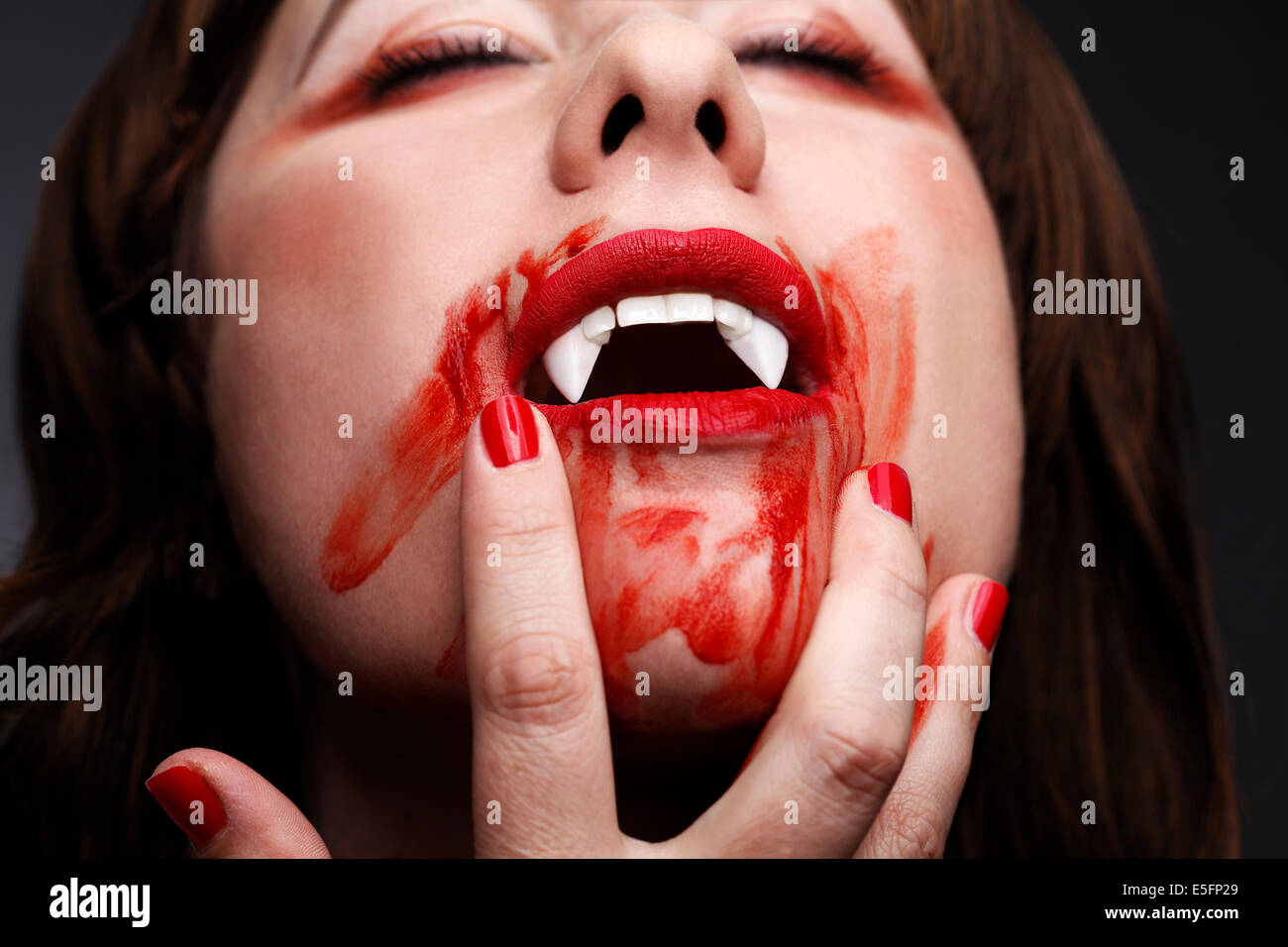 Vampiro femmina leccare il sangue dopo mordere Foto Stock