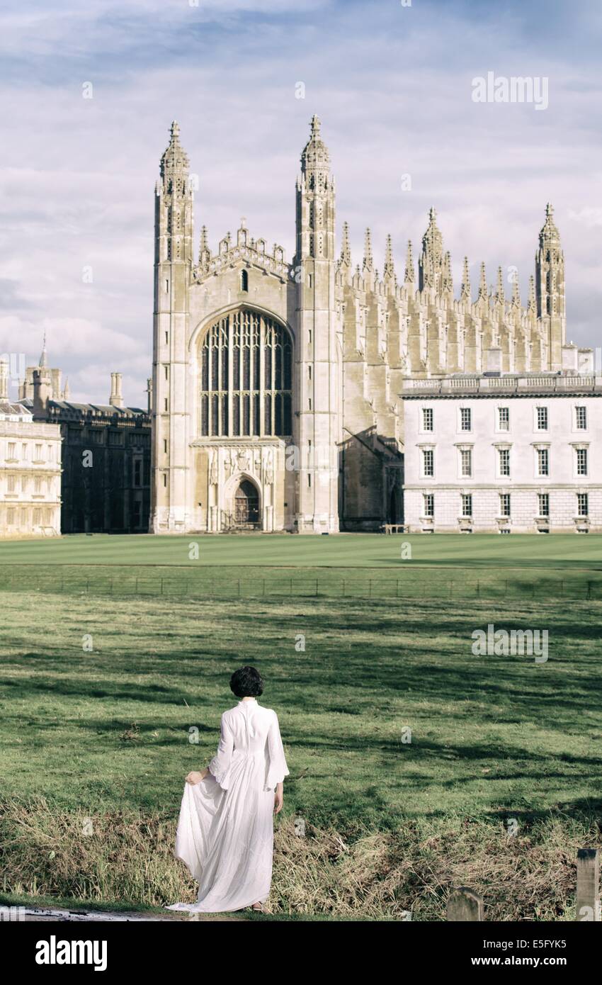 Una Donna vestita di bianco in piedi di fronte a King's College Chapel e spalle, Cambridge, Cambridgeshire, Regno Unito Foto Stock