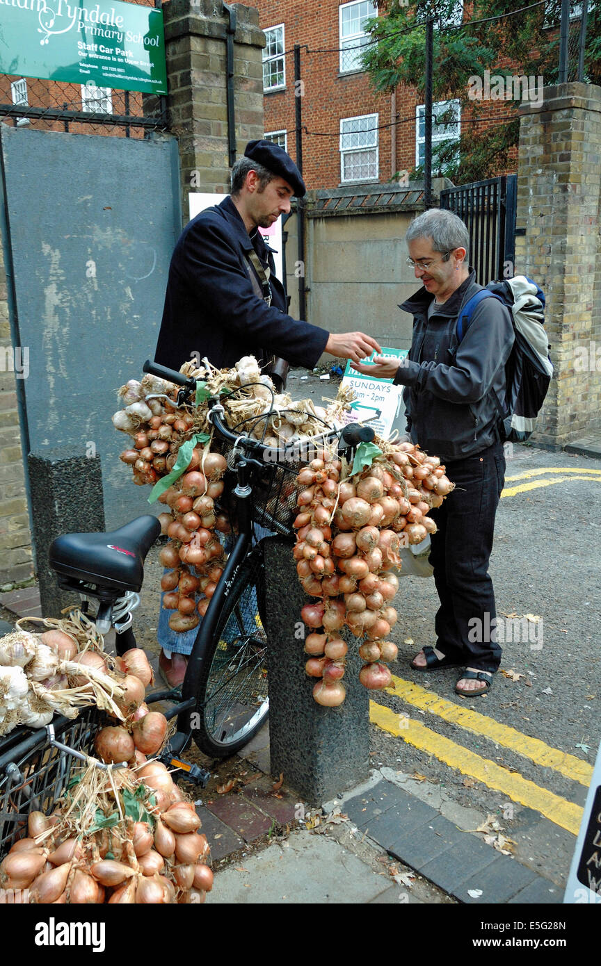 Cipolla francese venditore - uomo vendere le cipolle e aglio dalla bicicletta al di fuori del quartiere di Islington Farmers Market Londra Inghilterra REGNO UNITO Foto Stock