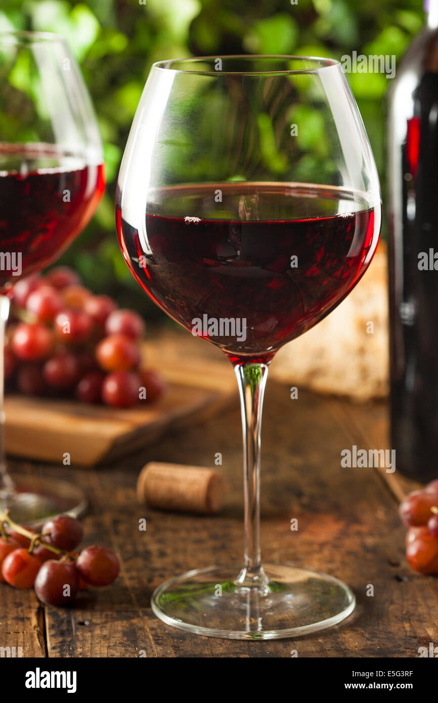 Rinfrescante vino rosso in un bicchiere con uve Foto Stock