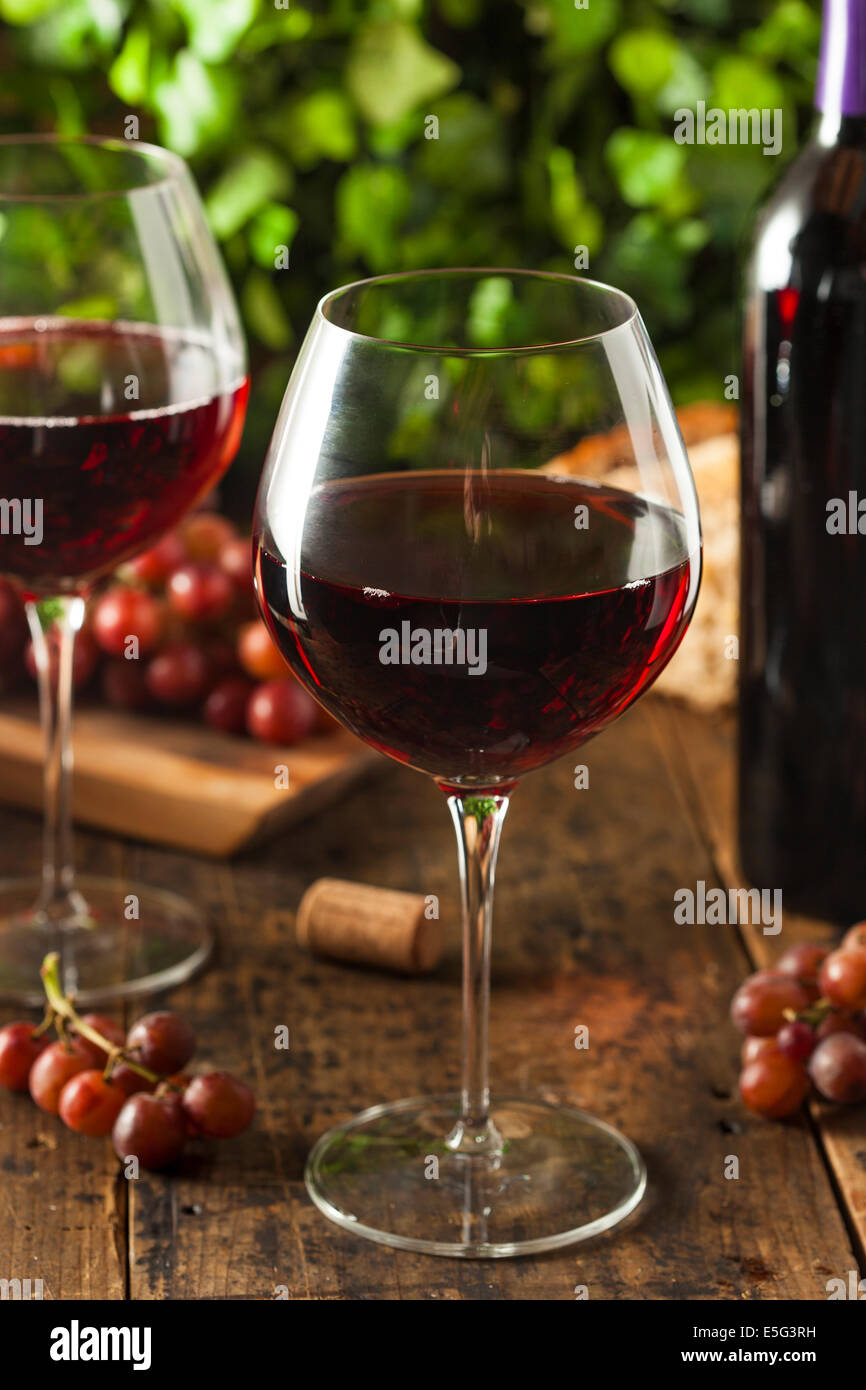 Rinfrescante vino rosso in un bicchiere con uve Foto Stock