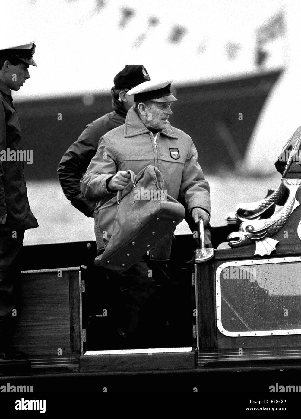 AJAXNETPHOTO. AGOSTO 1985. COWES, INGHILTERRA, - DUKE SI UNISCE ALLO YACHT - HRH IL PRINCIPE FILIPPO IL DUCA DI EDIMBURGO LASCIANDO LA CHIATTA REALE PER IMBARCARSI SU YEOMAN TWENTY DI OWEN AISHER PER LA GARA DI COPPA BRITANNIA. ROYAL YACHT BRITANNIA IN BACKGROUND. PHOTO;JONATHAN EASTLAND/AJAX REF:860308 Foto Stock