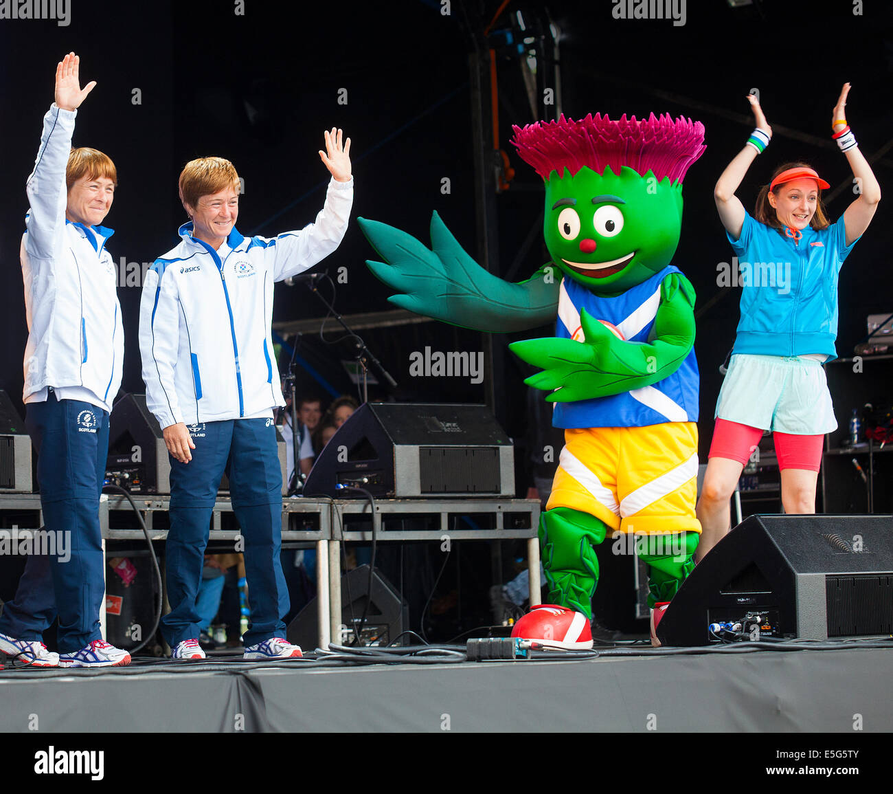 Glasgow, Scotland, Regno Unito. Il 30 luglio, 2014. Donna e Fiona Robertson, Team Scozia lottatori sul palco con Clyde, il Glasgow 2014 mascotte e Active Alice, in Glasgow Green durante il Festival 2014, un festival culturale in esecuzione in parallelo con i Giochi del Commonwealth a Glasgow, in Scozia. Foto Stock