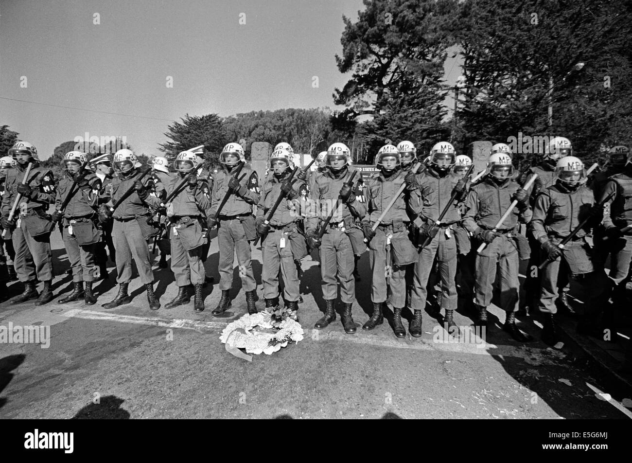 Anti-guerra di manifestanti giaceva un funerale corona ai piedi della polizia militare schierate per impedire ai dimostranti di entrare Presidio base navale di San Francisco, California. Foto Stock