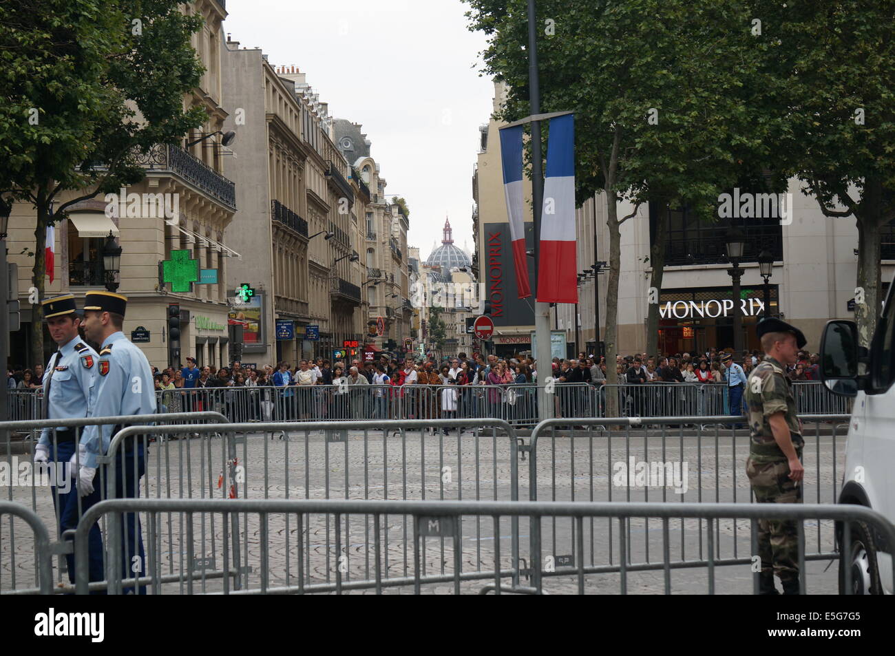 La folla di Parigi di fronte agli edifici dietro la folla di barriere di controllo su Avenue des Champs Elysees in attesa sul giorno della Bastiglia Foto Stock