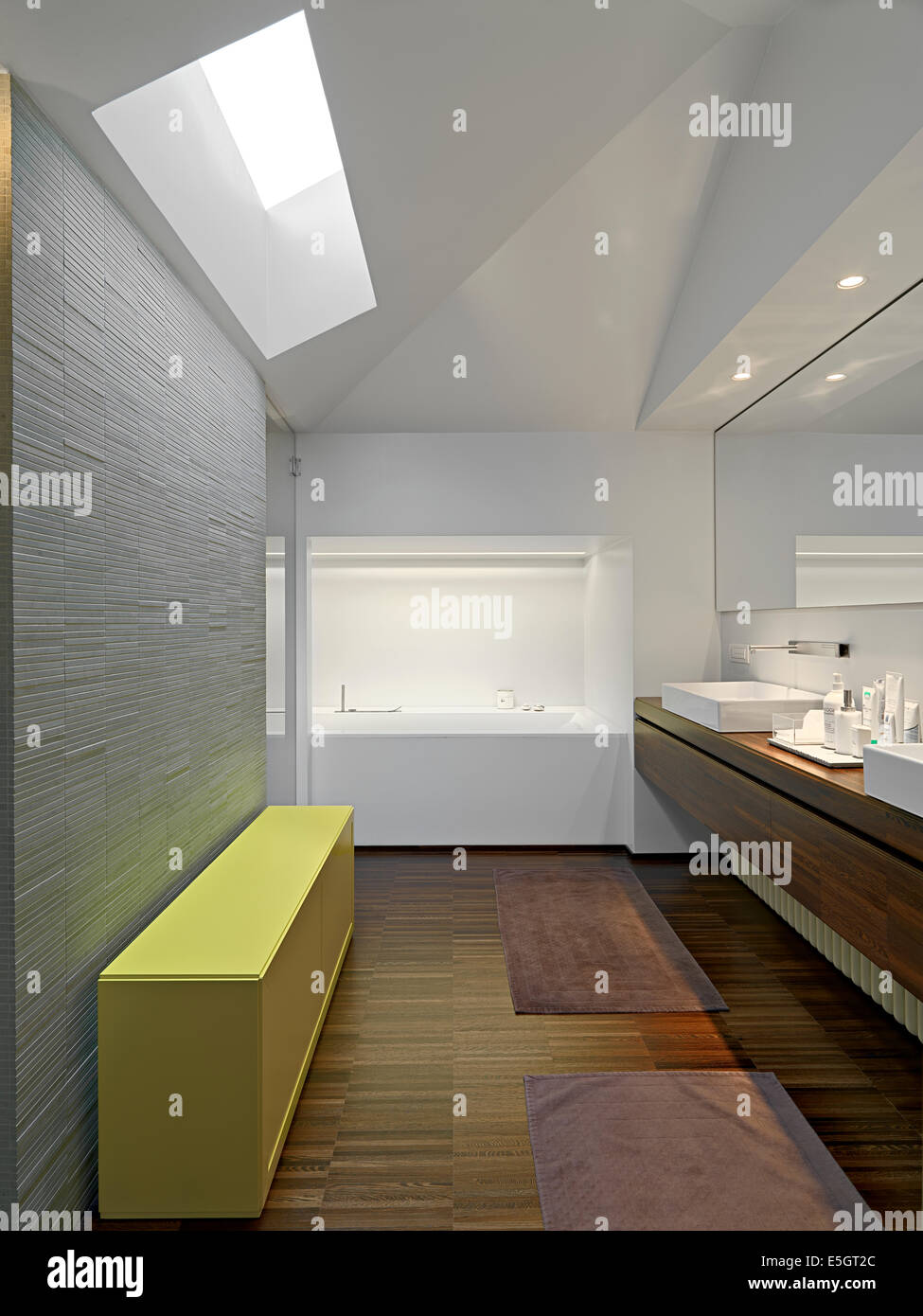 Vista interna di una moderna stanza da bagno al piano attico con mobili di colore giallo e pavimento in legno Foto Stock