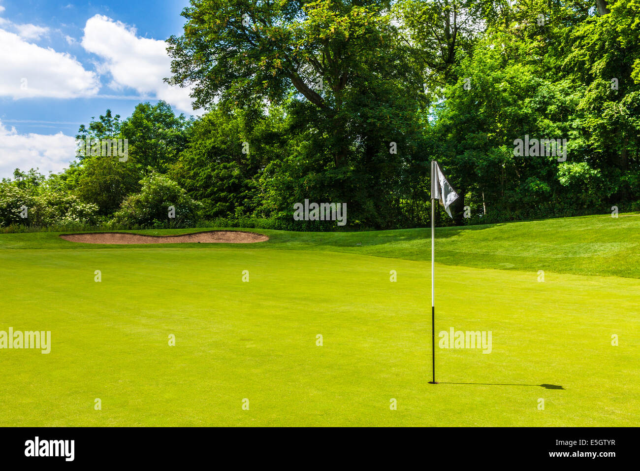 Un bunker e putting green con flagstick e foro su un tipico campo da golf. Foto Stock