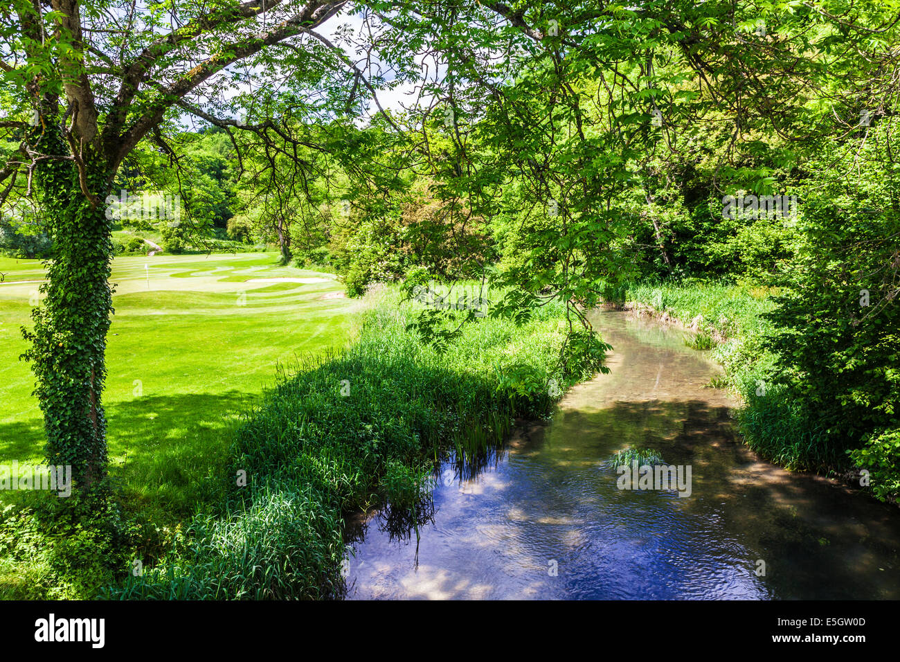 Il fiume Bybrook che scorre accanto a un campo da golf in Cotswolds. Foto Stock