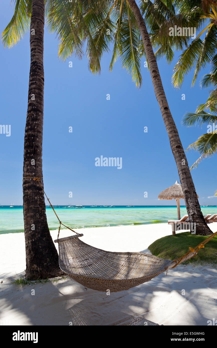 Amaca vuoto nei pressi di palme di cocco in spiaggia bianca Foto Stock