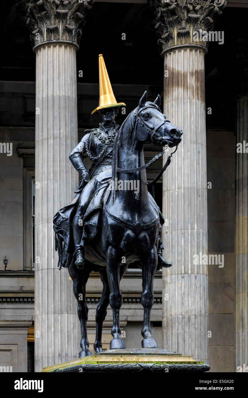 Glasgow, Scotland, Regno Unito. 31 Luglio, 2014. Nella celebrazione del successo dei Giochi del Commonwealth, il regolare e iconico rosso e bianco cono di traffico sulla testa del Duca di Wellington statua (normalmente messi lì come uno studente beffa) è stato sostituito da un dipinto di oro. La statua, con un cono di traffico sulla parte superiore, al di fuori della Galleria di Arte Moderna di Royal Exchange Square è stato utilizzato come un esempio di umorismo Glaswegian ed è un continuo interesse per i turisti e la gente del posto. Credito: Findlay/Alamy Live News Foto Stock