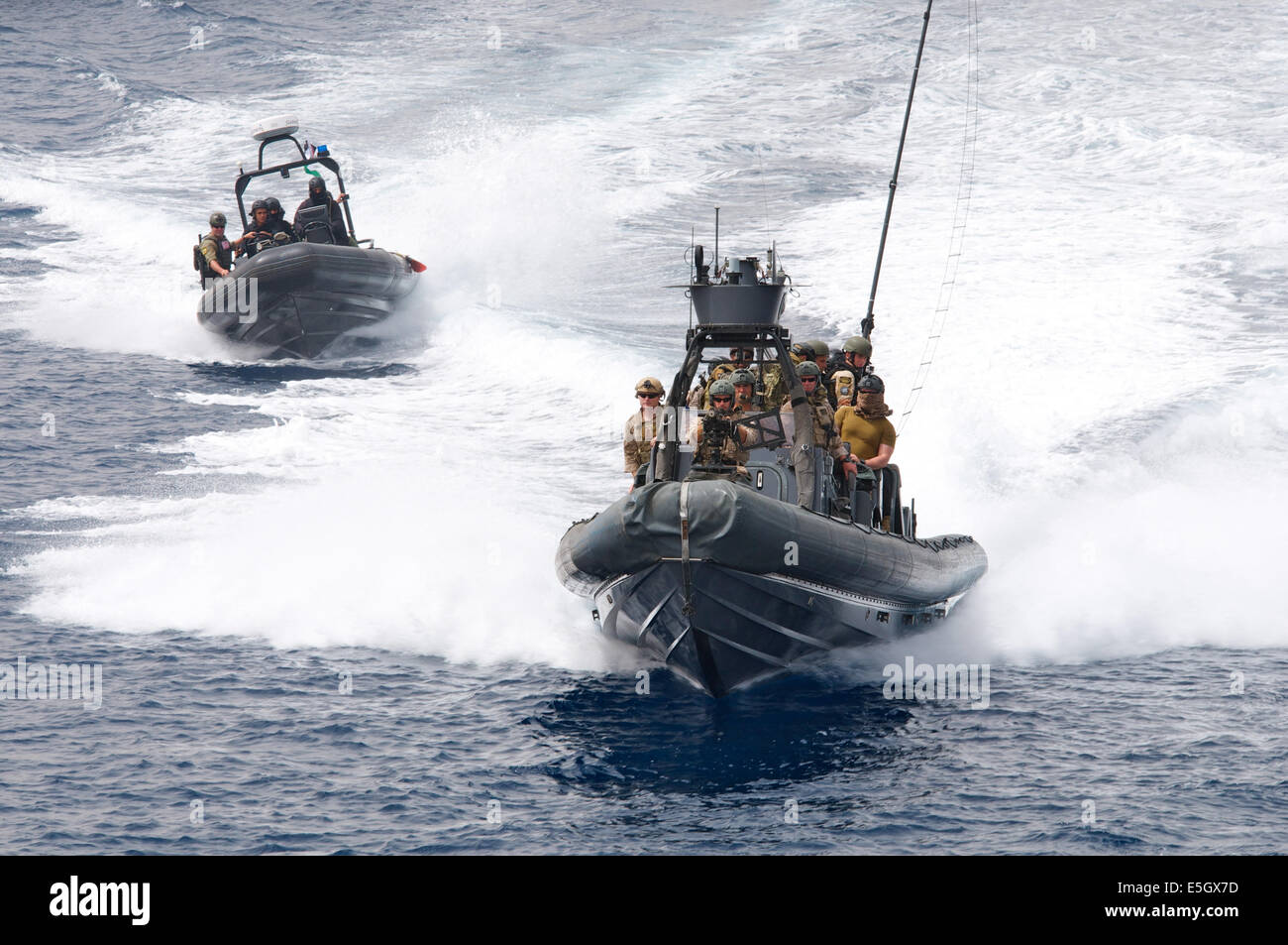 Multinazionale di forze per le operazioni speciali membri ride a bordo di U.S. Navy rigida-hull imbarcazioni gonfiabili verso una nave da crociera durante una Foto Stock