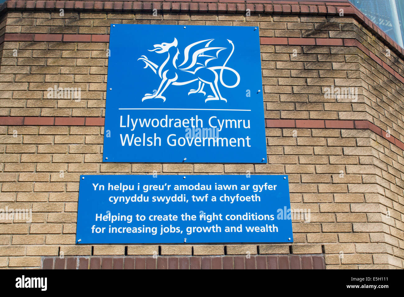 Governo gallese cartello bilingue al di fuori ufficio edificio " Aiutare a creare le giuste condizioni per aumentare i posti di lavoro, crescita e Foto Stock