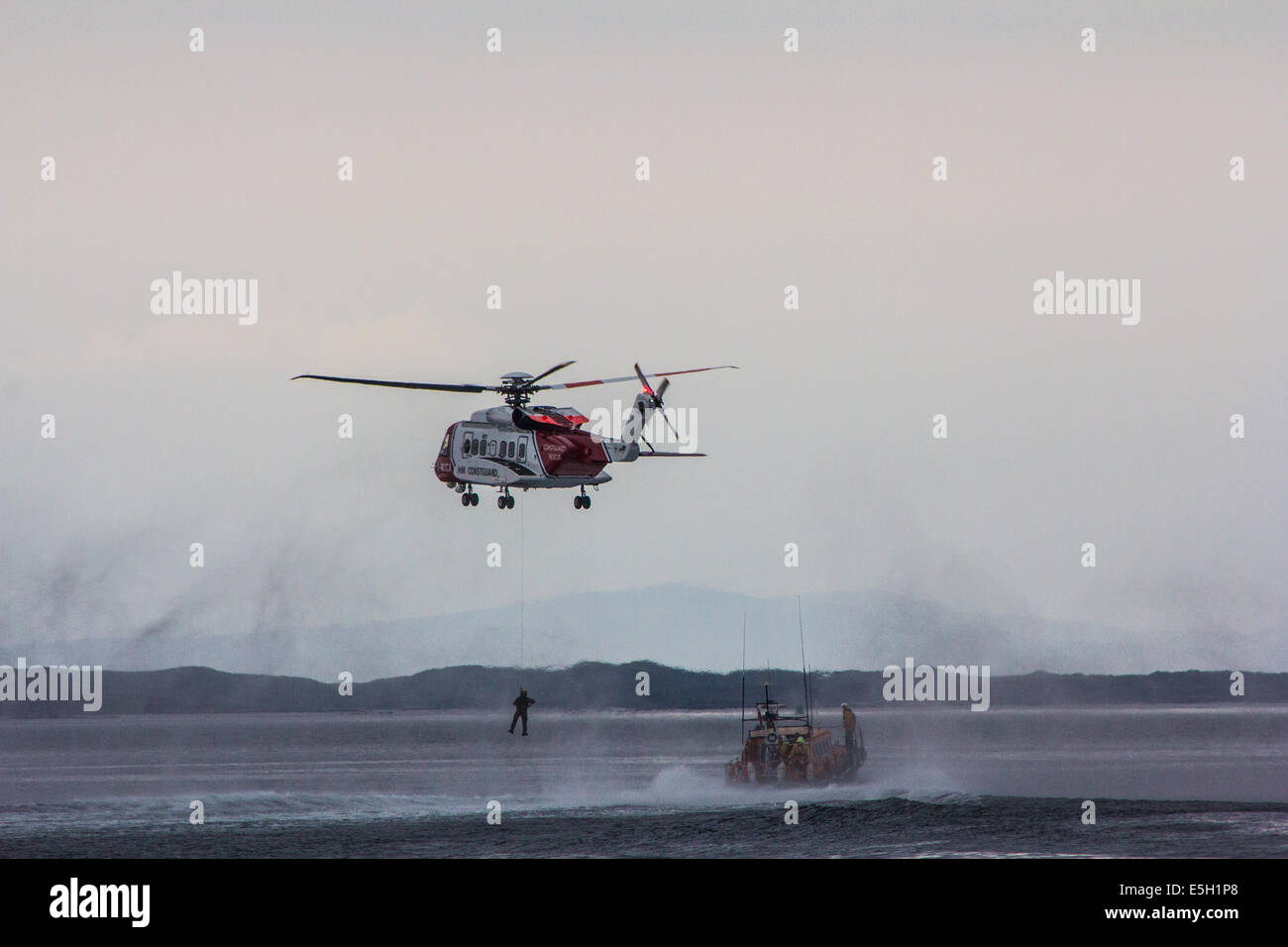 Una guardia costiera elicottero winching uomo per la sicurezza Foto Stock