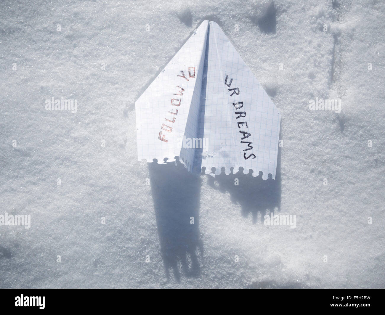 Aeroplano di carta sul bianco della neve con seguire i tuoi sogni frase Foto Stock