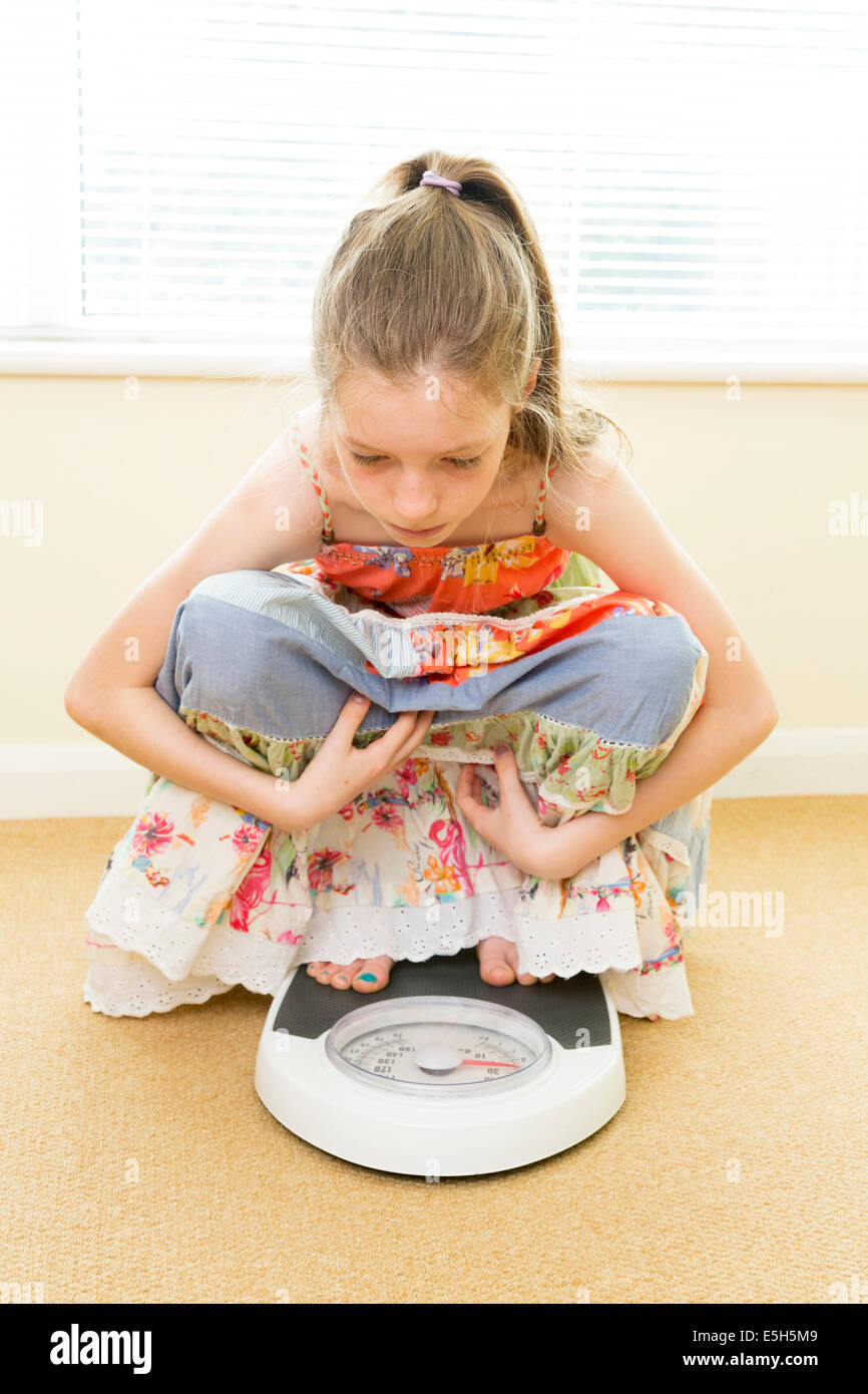 Ragazza giovane controllando il suo peso sulla bilancia Foto Stock