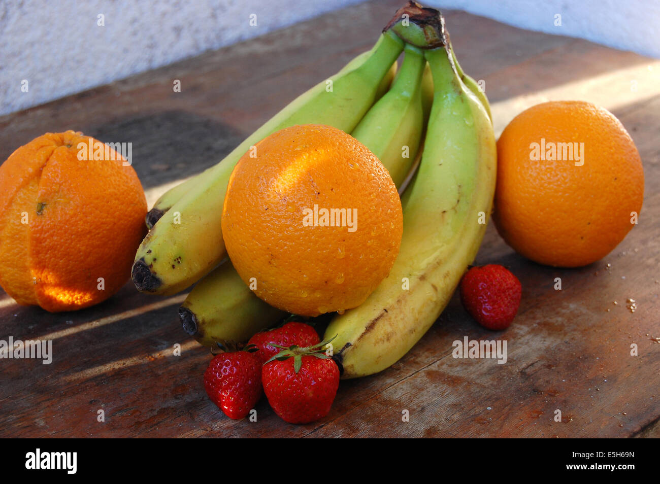 Arance, fragole e banane fotografato su una tavola di legno Foto Stock