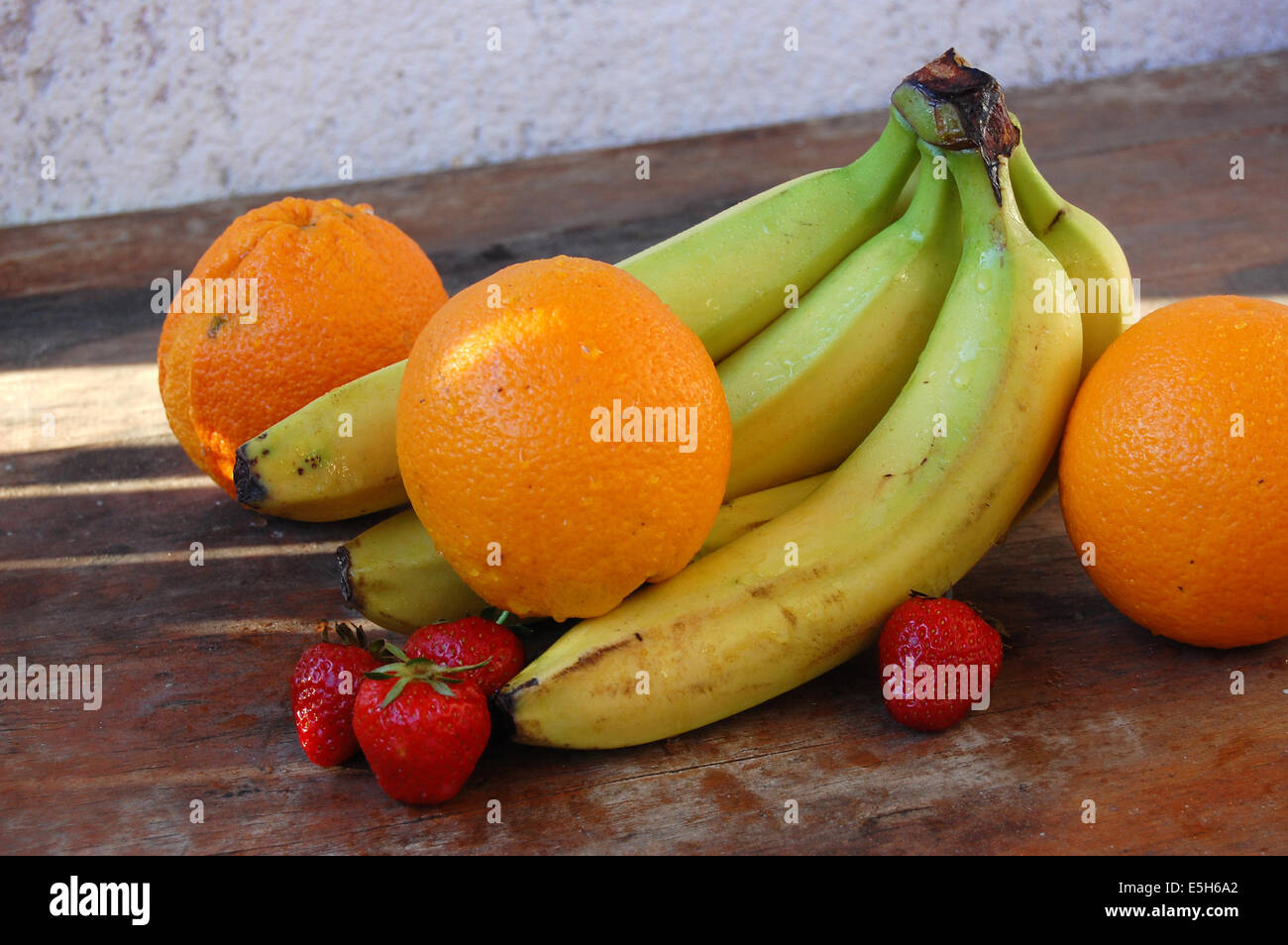 Arance, fragole e banane fotografato su una tavola di legno Foto Stock