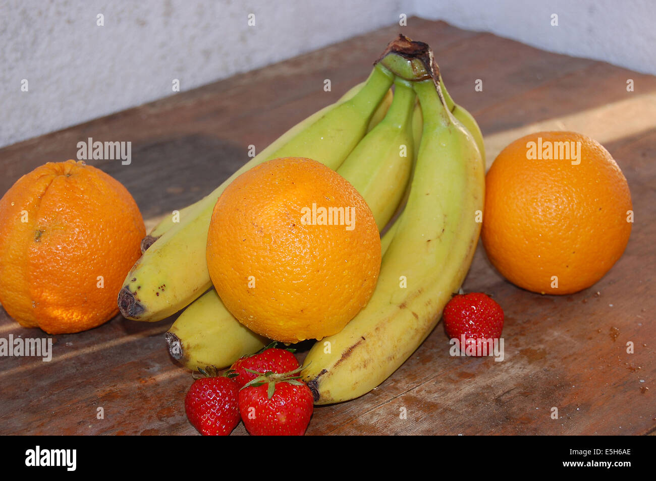 Arance, fragole e banane fotografato su una tavola di legno Foto Stock