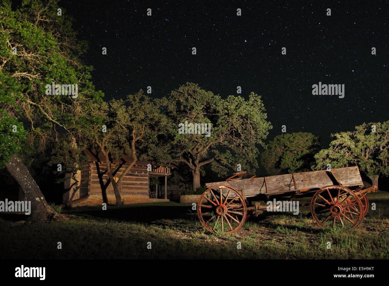Un vecchio carro di legno con ruote arrugginito appoggiata sotto le stelle di notte in un campo di fattoria in Texas, Stati Uniti d'America. Foto Stock