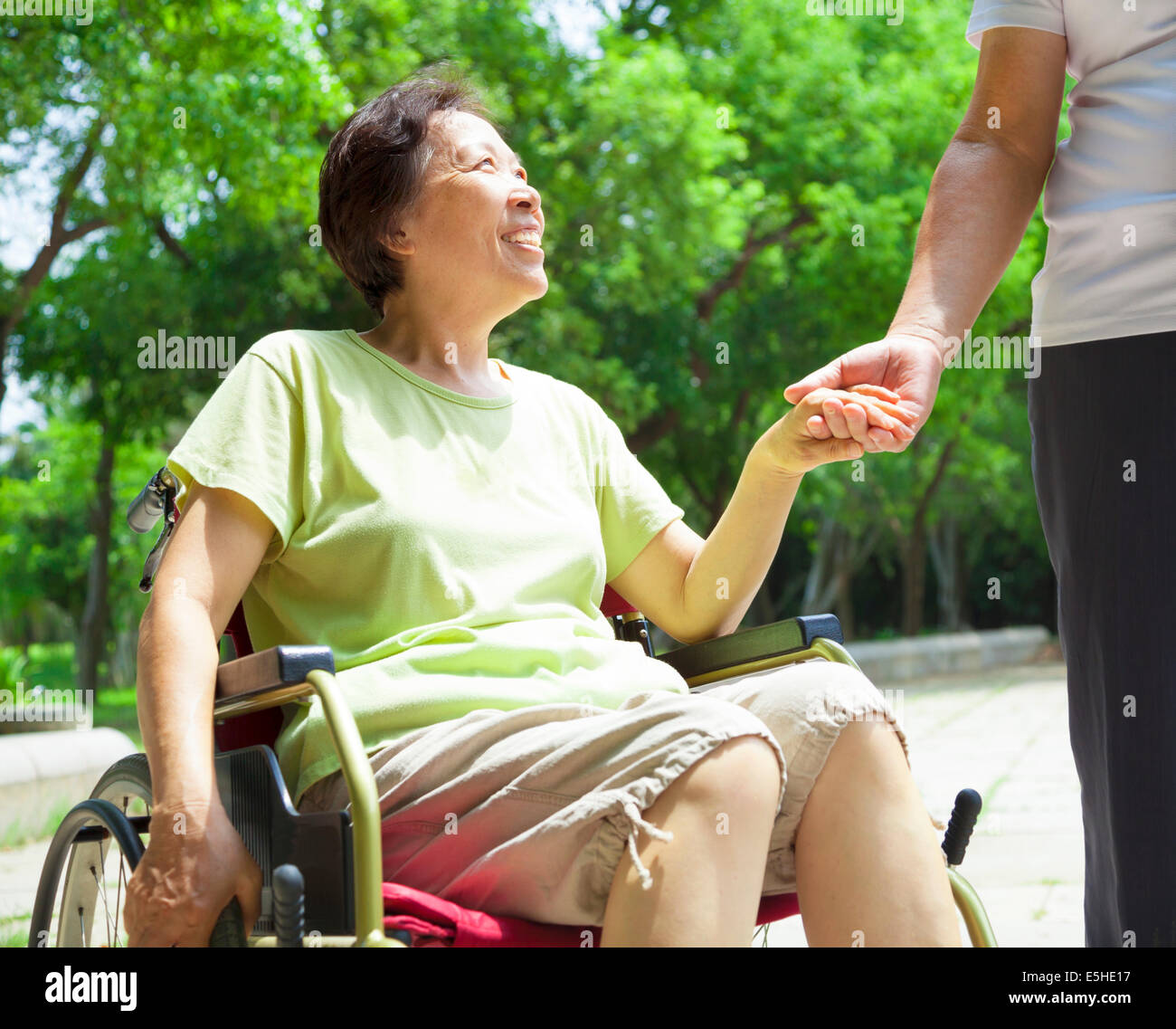 Senior l'uomo con sua moglie di disabili su sedia a rotelle Foto Stock