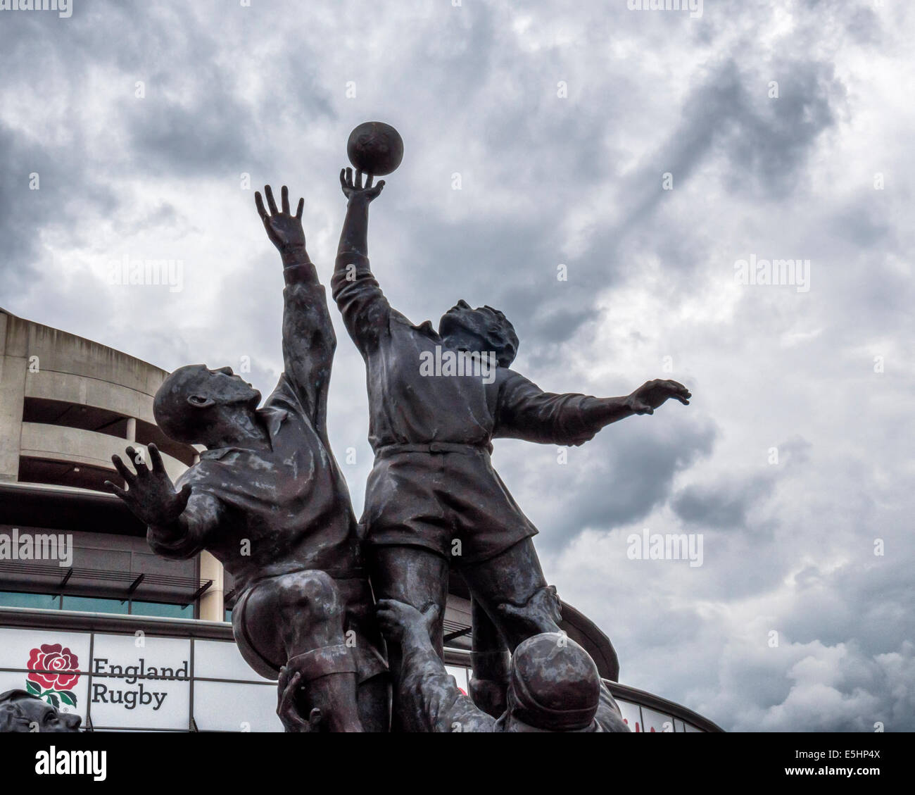 Il Twickenham Rugby Stadium e la scultura in bronzo di giocatori di rugby saltando in un pallone da rugby, London, England, Regno Unito Foto Stock