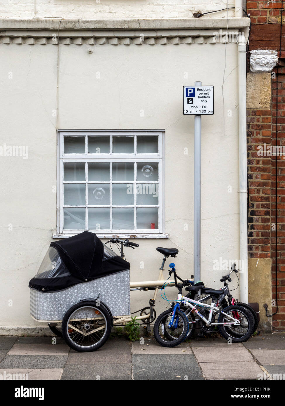 Bicicletta con bambino vettore o baby carrier per bambini e biciclette parcheggiate fuori una casa a Twickenham, London, Regno Unito Foto Stock