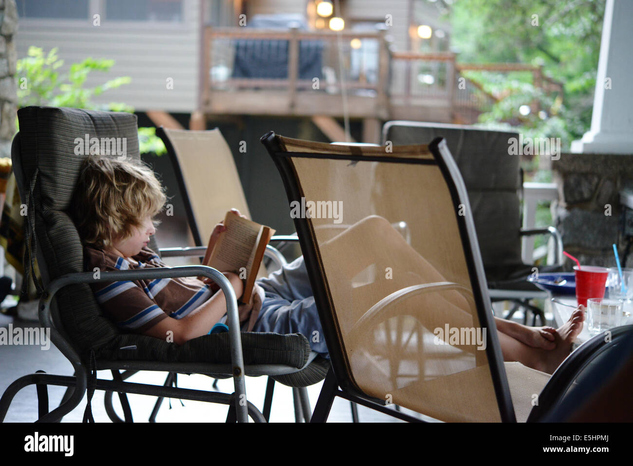 Capelli biondi kid lettura sul portico Foto Stock