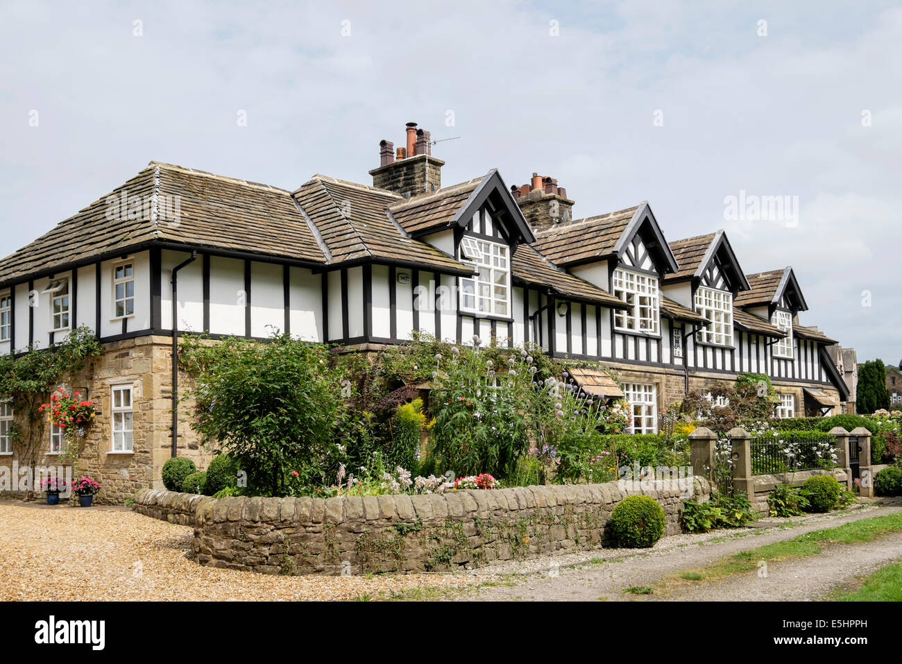 Riga del XIX secolo in stile Tudor case a schiera (1882) con Giardini da cottage in estate. Whalley, Lancashire, Inghilterra, Regno Unito, Gran Bretagna Foto Stock