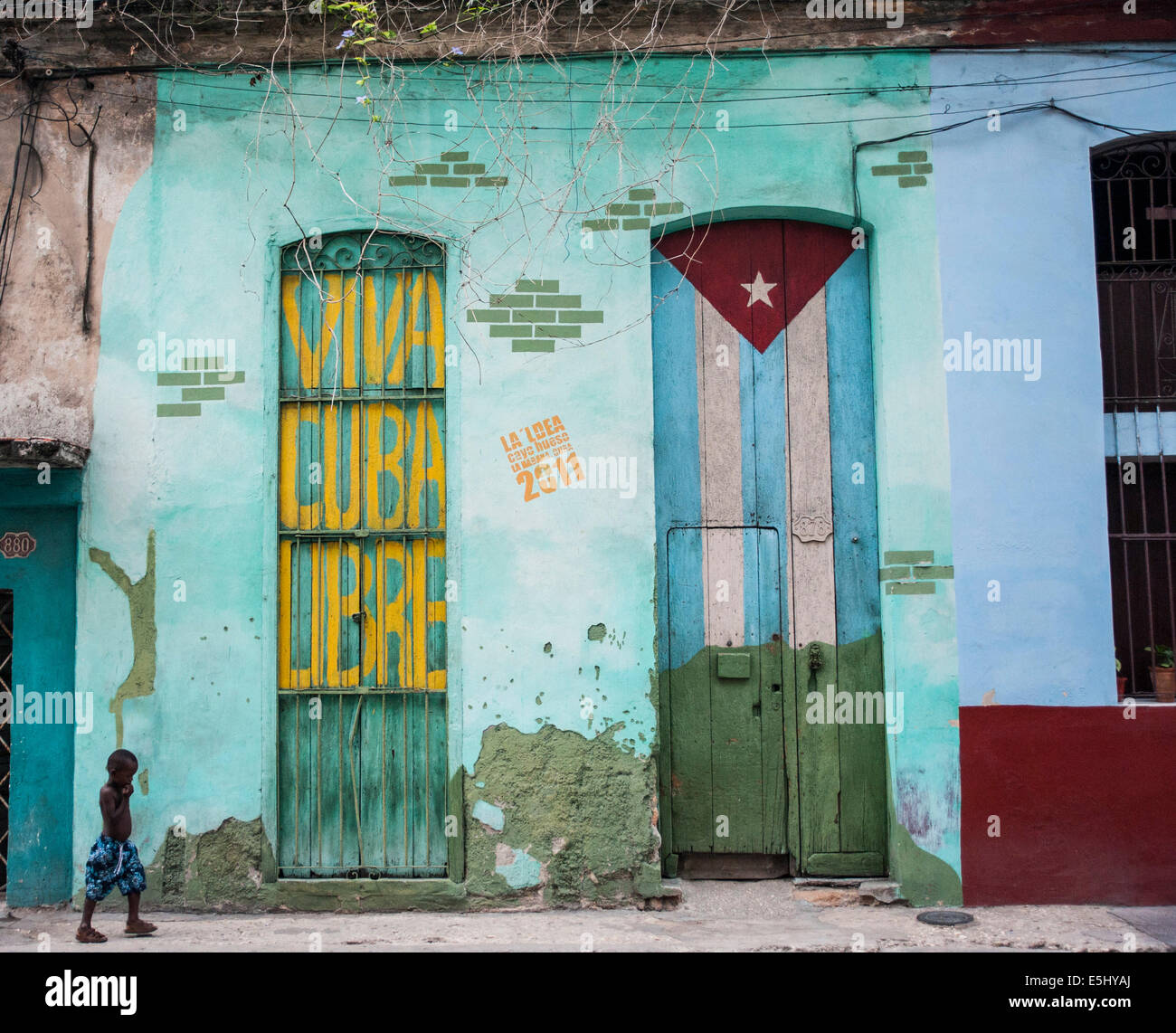Bambino passeggiate passato murale su edificio con la scritta Viva Cuba Libre di Havana, Cuba Foto Stock