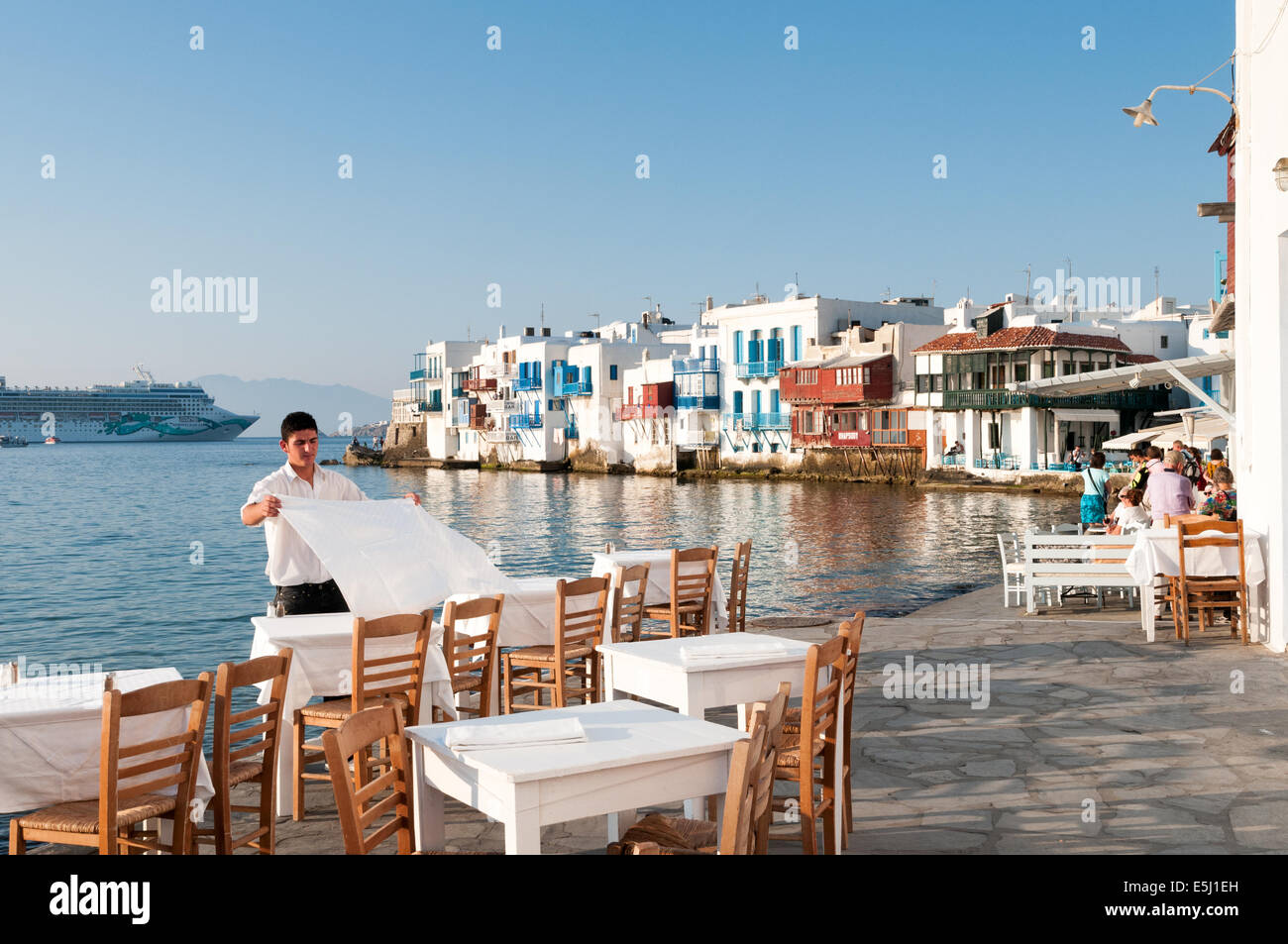 Cameriere che stabilisce le tabelle a waterfront restaurant nella piccola area di Venezia di Mykonos, Grecia Foto Stock