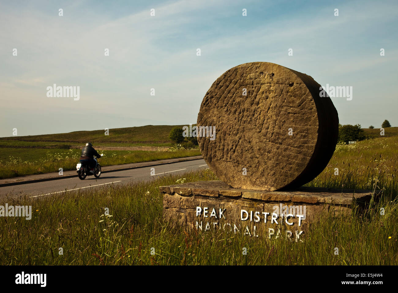 Un motociclista solitario passeggiate nel Parco Nazionale di Peak District passato uno del parco segni di pietra Foto Stock