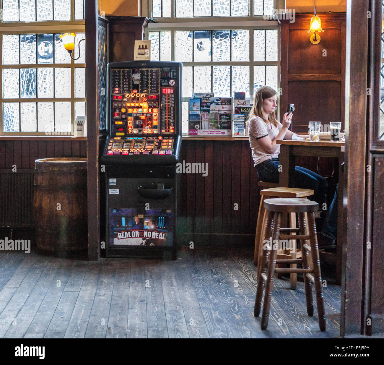 "Il mercato Porter' interni - all'interno di un tradizionale pub di Londra con la macchina da gioco e donna seduta su sgabello - Londra, Regno Unito Foto Stock