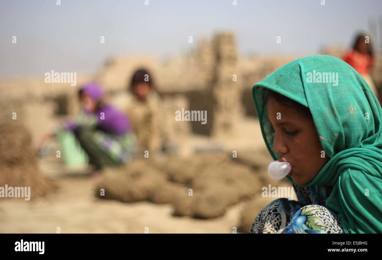 A Kabul, Afghanistan. 2 agosto, 2014. Una ragazza afgana mastica la gomma come lavora in una fabbrica di mattoni a Kabul, Afghanistan, 2 agosto 2014. Migliaia di bambini afgani lavoro per sostenere le loro famiglie. © Ahmad Massoud/Xinhua/Alamy Live News Foto Stock