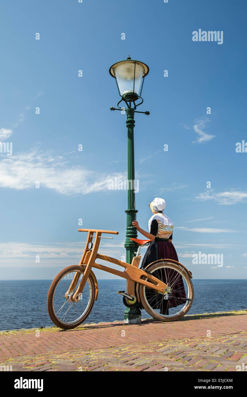 Paesi Bassi, Urk, Fronda Bike. Il design olandese bici in legno è una creazione di Jan Gunneweg. Ragazza nel tradizionale abito della domenica Foto Stock