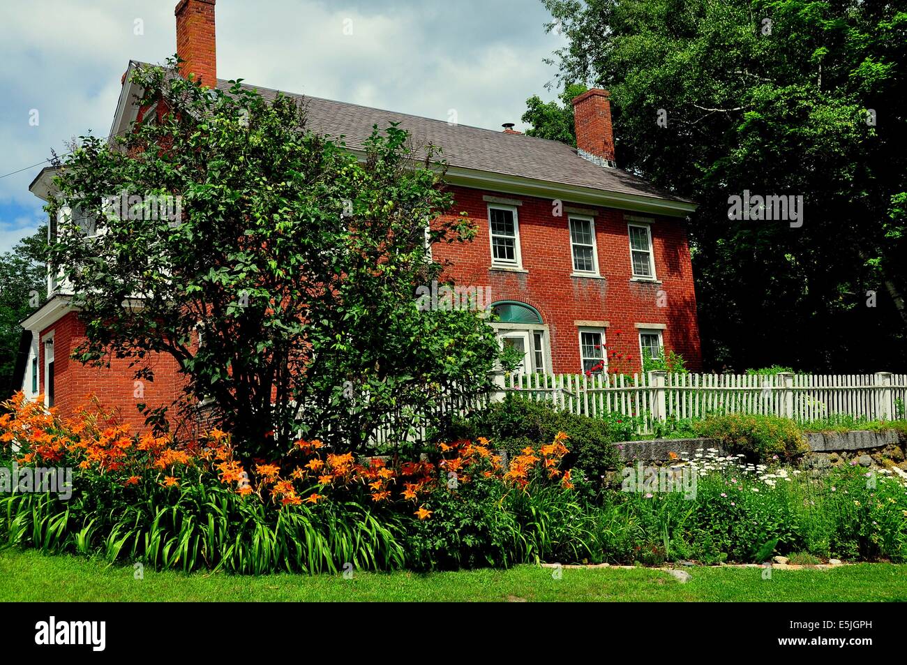 HARRISVILLE, New Hampshire: bello inizi del XIX secolo casa di mattoni con orange giorno Gigli Foto Stock