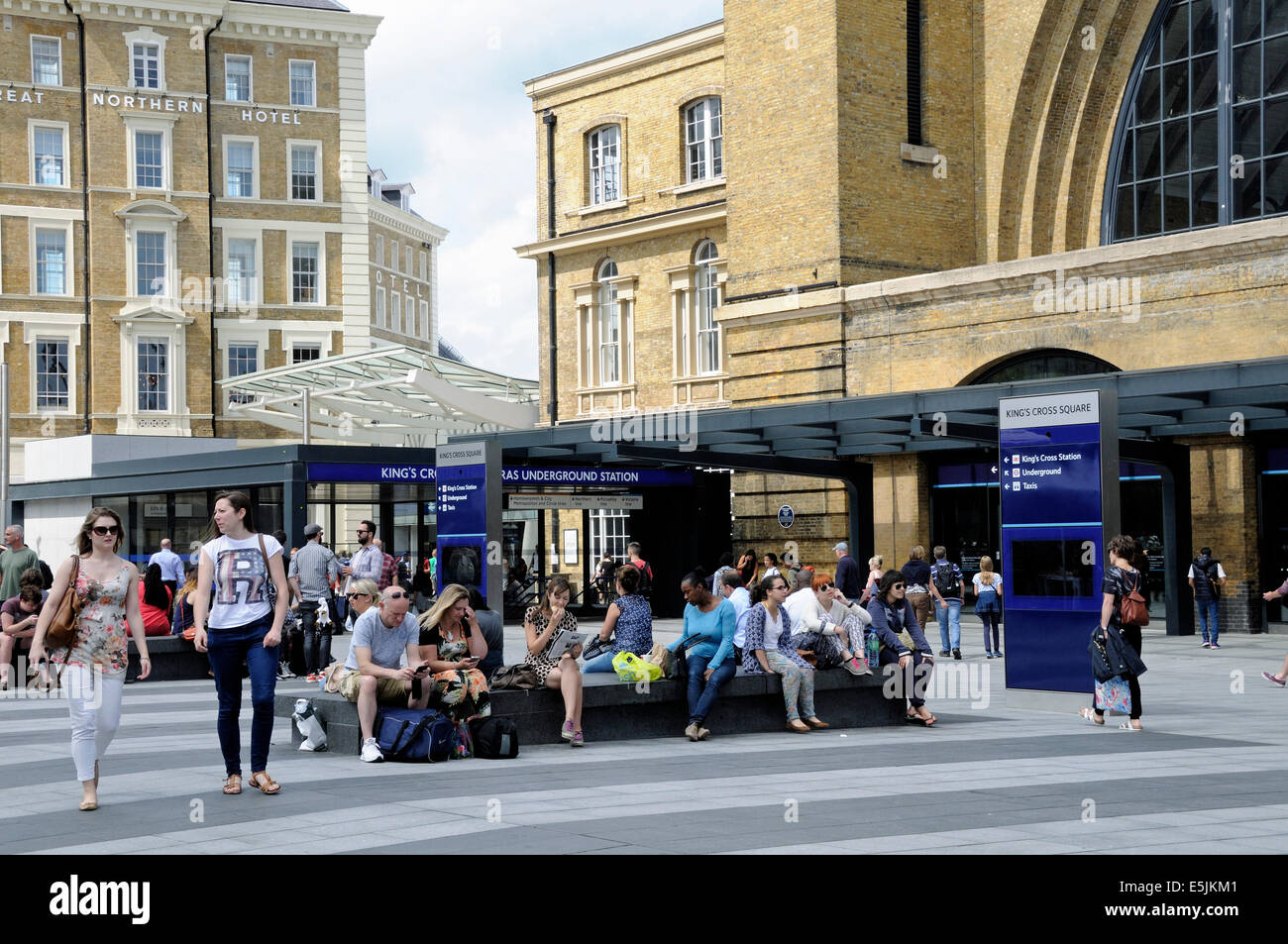 Le persone sedute a Kings Cross Station Square, Londra, Inghilterra Gran Bretagna REGNO UNITO Foto Stock