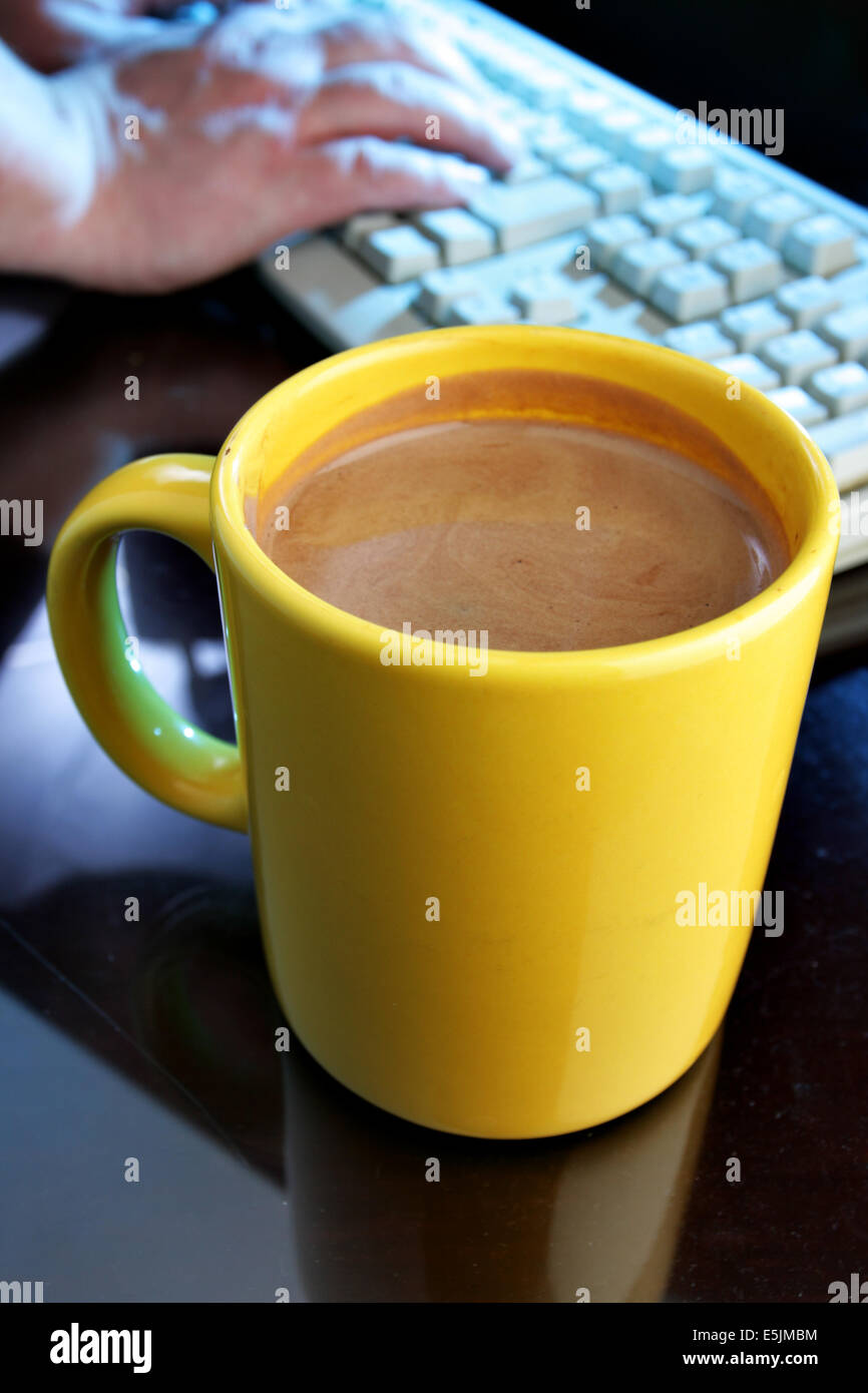Giallo tazza da caffè e la tastiera in background. DOF poco profondo! Foto Stock