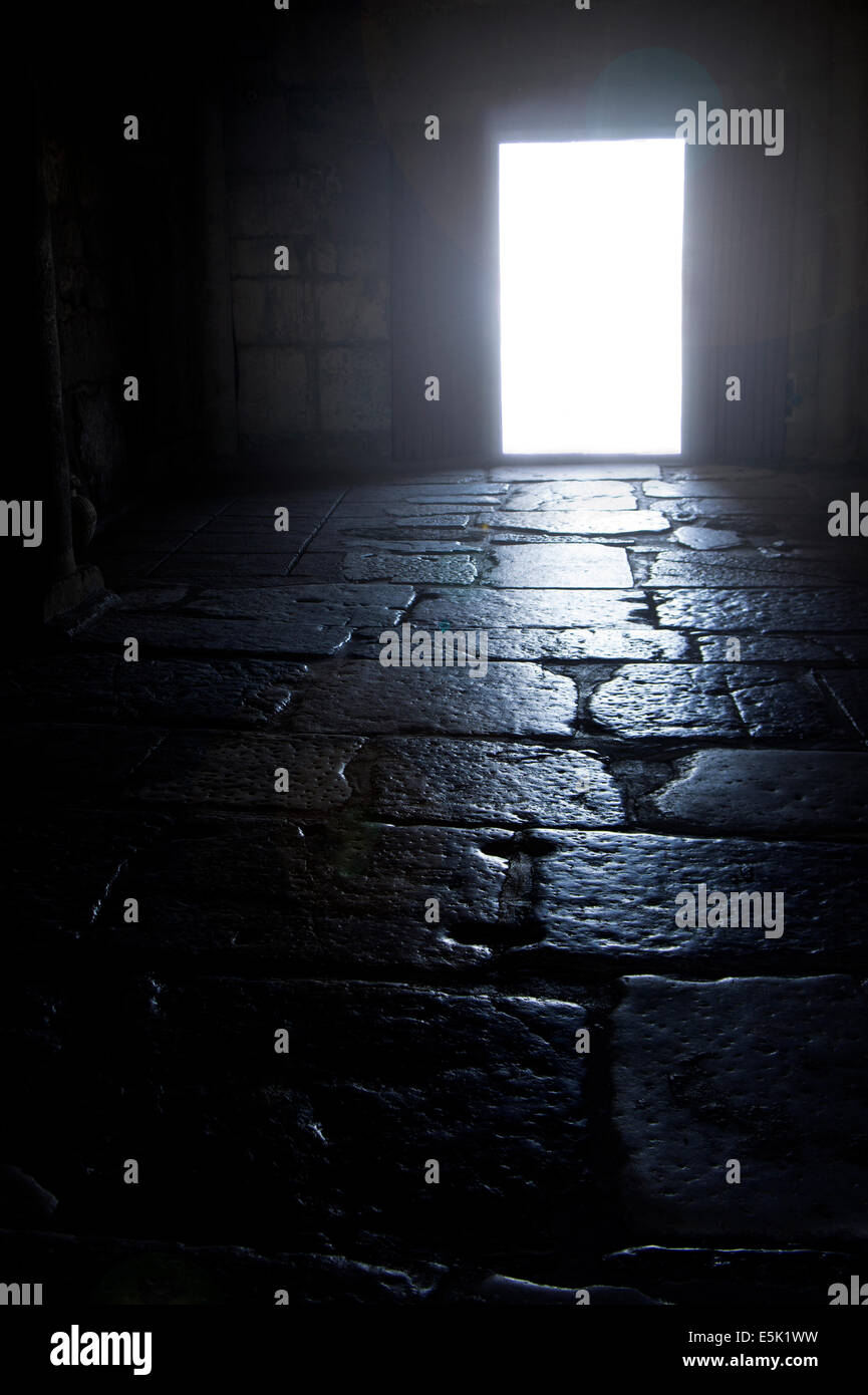 Dark vecchio pavimento in pietra camera con luce intensa la rottura attraverso lo sportello Foto Stock