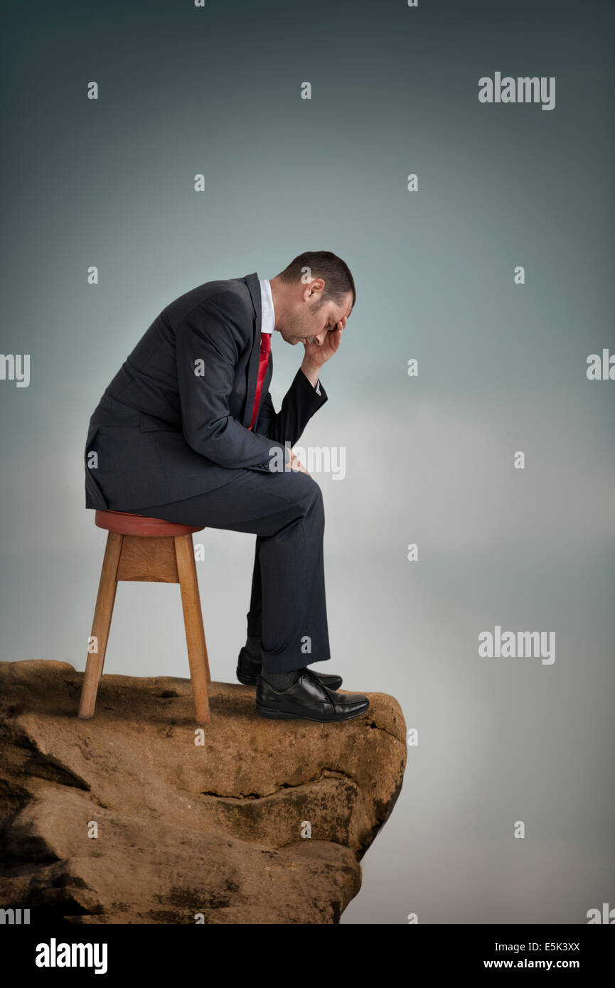 Premuto imprenditore sofferenza depressione su una scogliera battuta Foto Stock