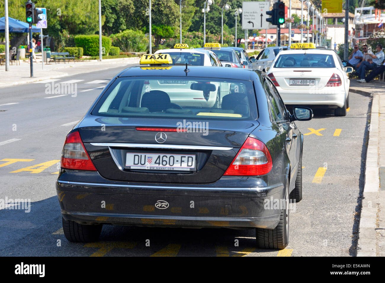 Gruppo di taxi ufficiale di parcheggio su strada baie con giallo montato sul tetto i segni e i piloti seduti in ombra Foto Stock
