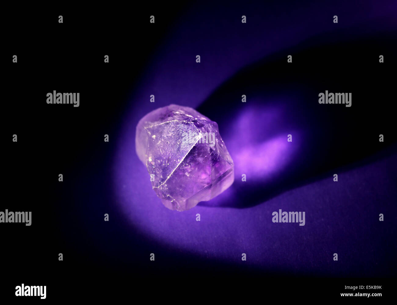 Ametista cristallo illuminato macro su sfondo viola. Foto Stock