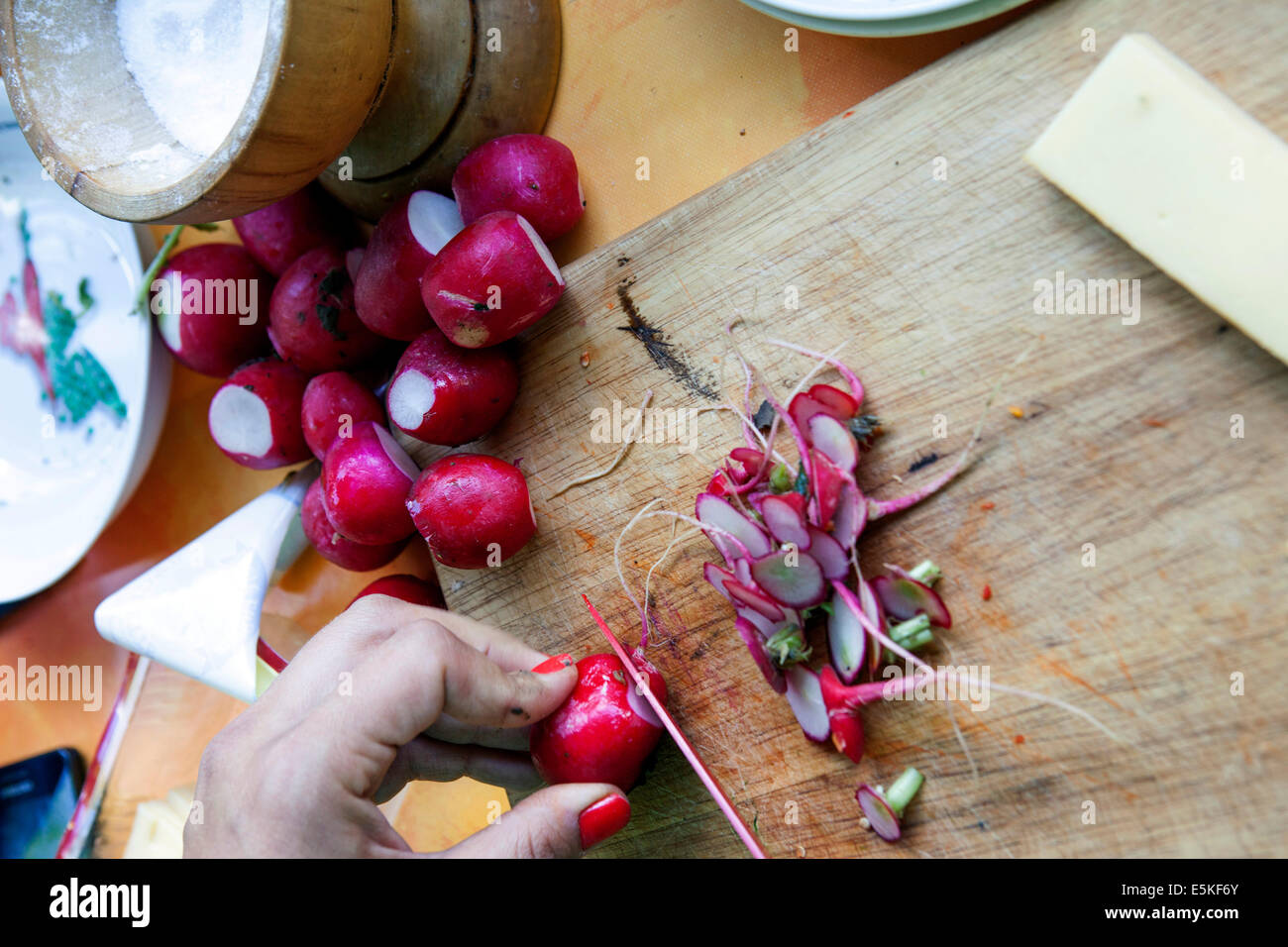Dettaglio del tagliere e del coltello che tagliano ravanelli freschi Foto Stock